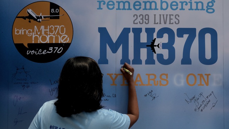 person signing a MH370 billboard