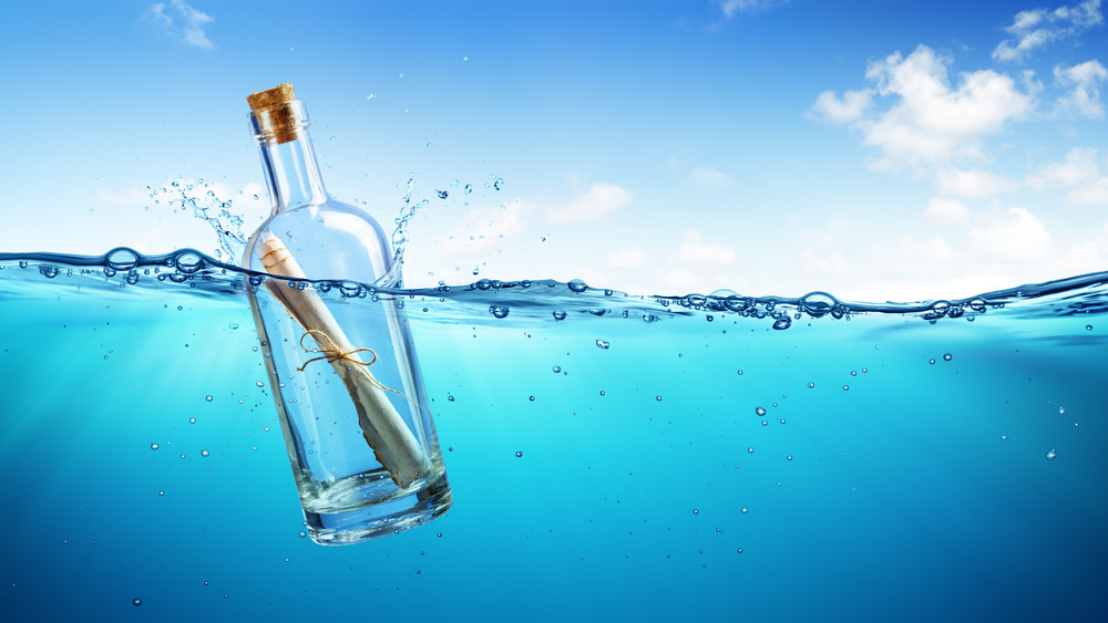 Bottle with message inside floating in water