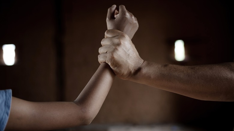 Man grabbing young person's arm