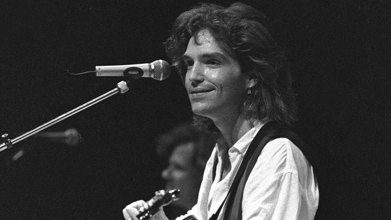Richard Marx smiling and playing guitar on stage