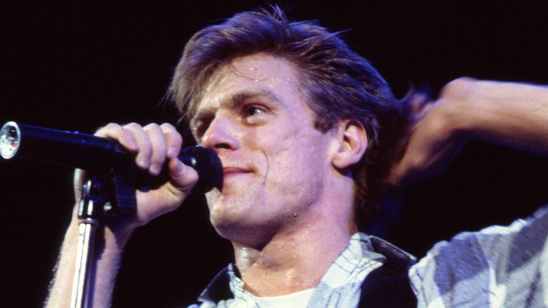Bryan Adams singing into microphone onstage