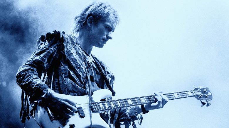 Sting playing guitar on stage lit in blue