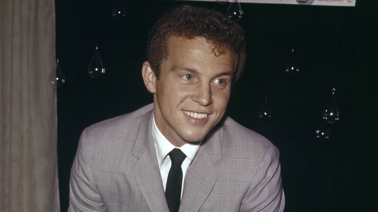 Bobby Vinton smiling and wearing a gray suit jacket with white shirt and black tie