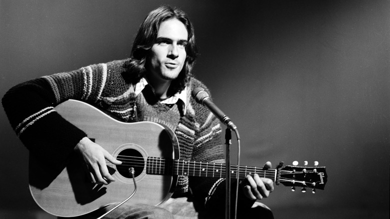 James Taylor playing guitar in concert