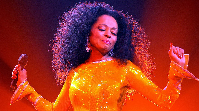 Diana Ross striking a pose on stage in orange dress