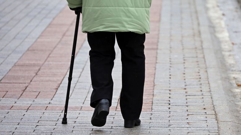 old woman walking down the street with a cane