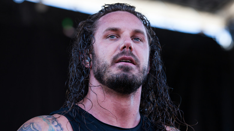 Tim Lambesis on stage in black vest with beard staring