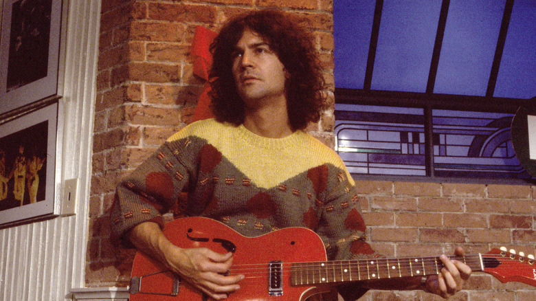 Billy Squier long hair and sweater playing guitar