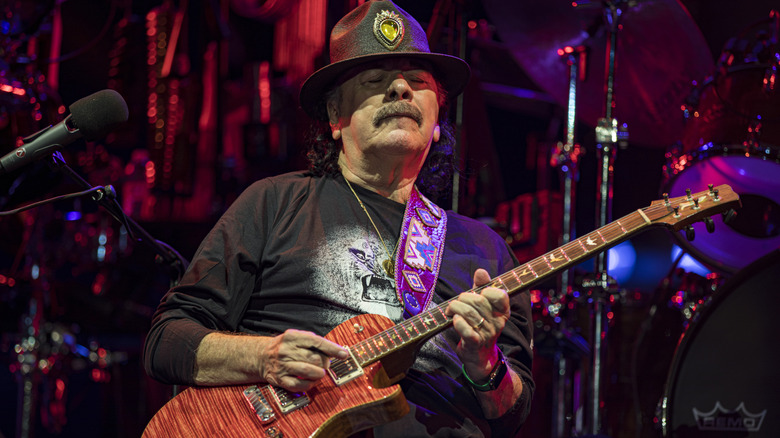 Carlos Santana wearing a hat and playing guitar on stage