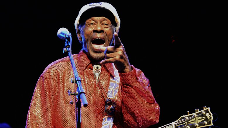 Chuck Berry in hat with mouth open pointing on stage