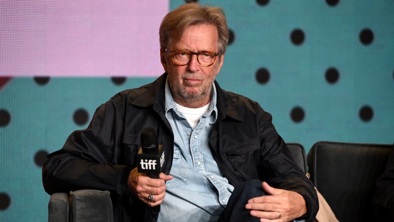eric clapton in glasses sitting holding mic