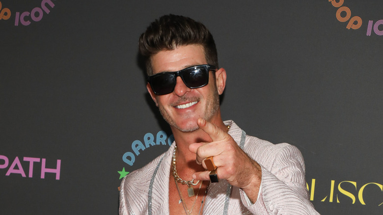 Robin Thicke smiling and pointing in sunglasses at event