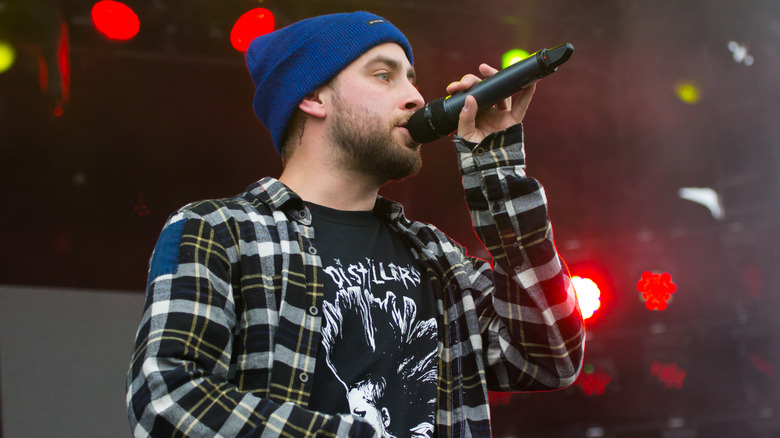 Tyler Carter wearing a blue beanie singing on stage