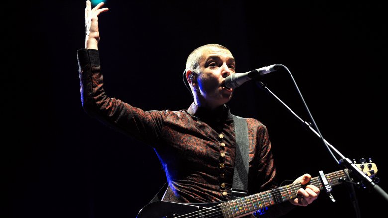 Sinead O'Connor singing with guitar and arm raised