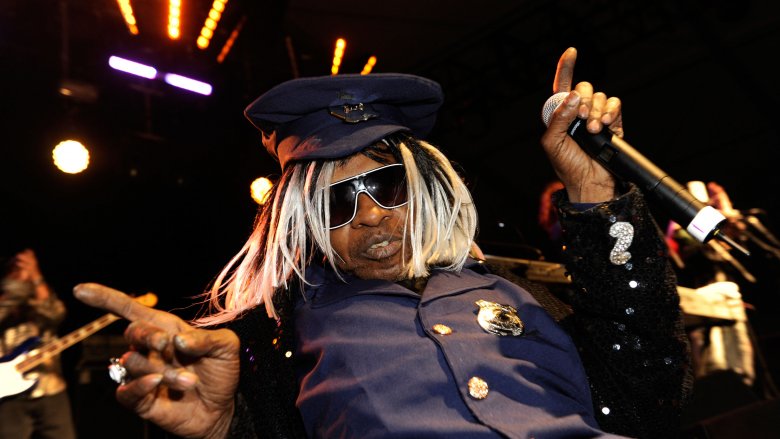 sly stone pointing in police uniform on stage holding mic