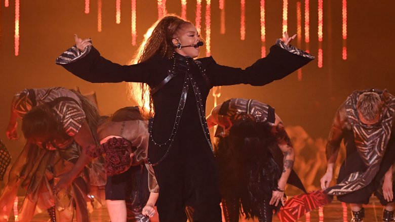 Janet Jackson singing arms raised with backing dancers