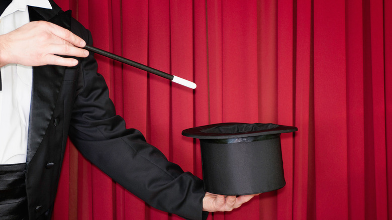 Magician waving wand over hat