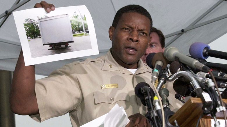 Charles Moose holding up a photo at a press conference