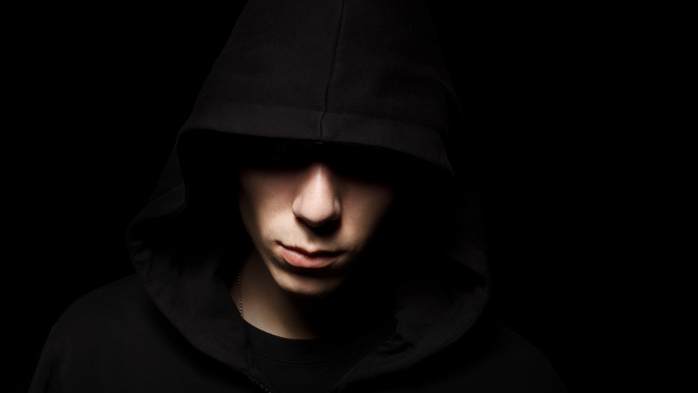 creepy young man threatening hooded