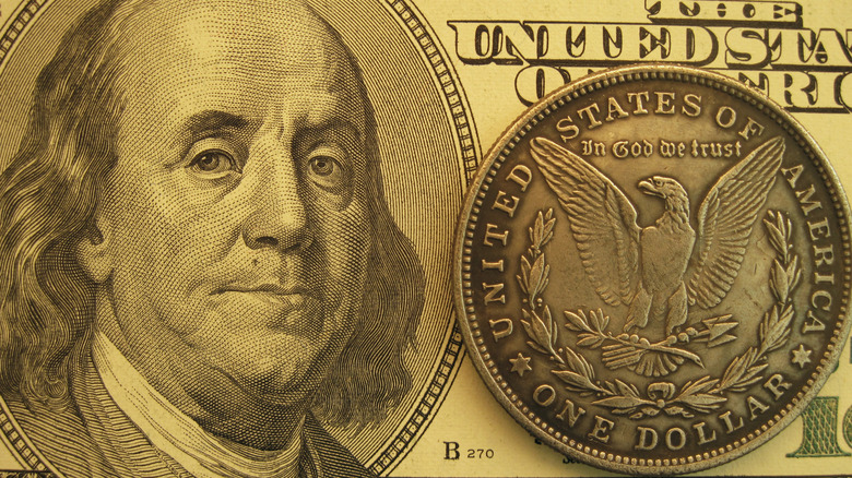 One hundred dollar bill and the reverse side of a Morgan silver dollar