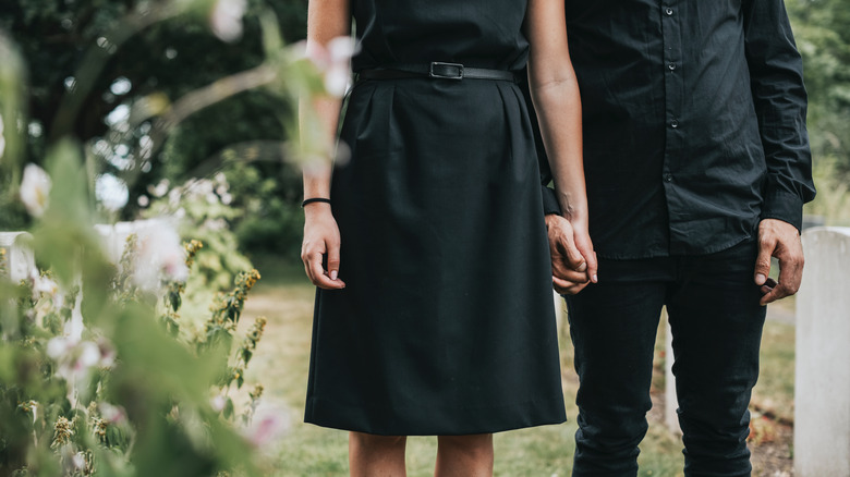 Couple in black holding hands at funeral