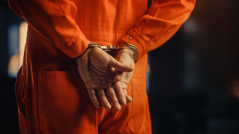 Prisoner in orange jumpsuit cuffed