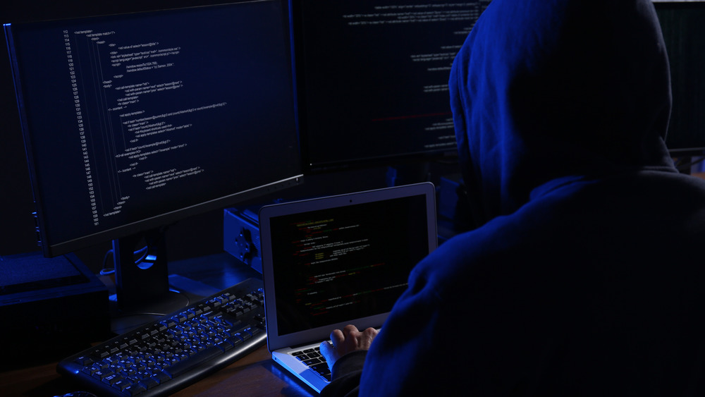 Hacker with computers in dark room