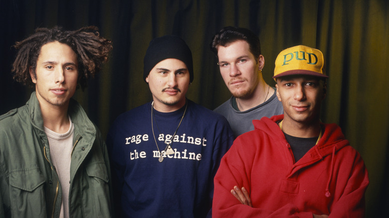 Rage against the machine posing in front of a curtain.