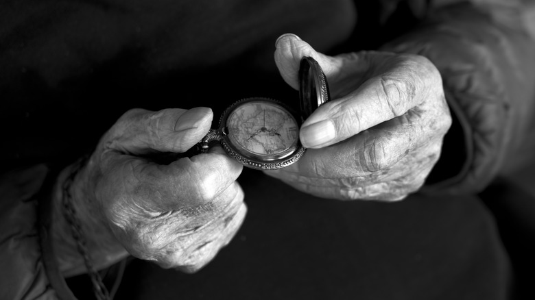 An old man's hands holding a pocket watch