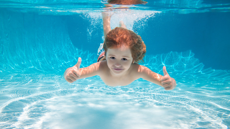 Child swimming underwater giving double thumbs up