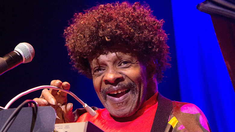 Sly Stone sitting behind a keyboard smiling