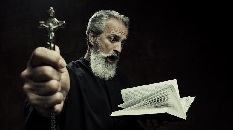 exorcist with cross performing rites
