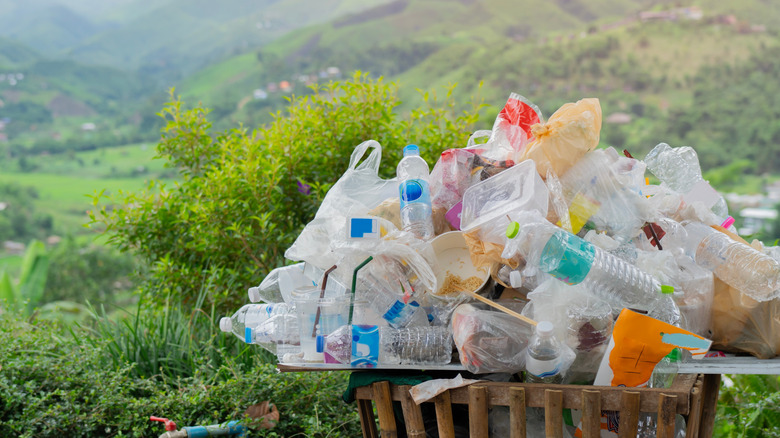Plastics overflowing in garbage can in natural landscape