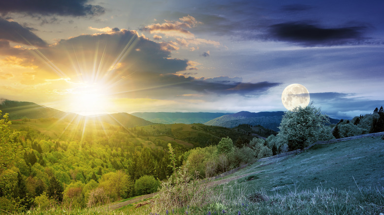 Sunset and moon in sky above fields