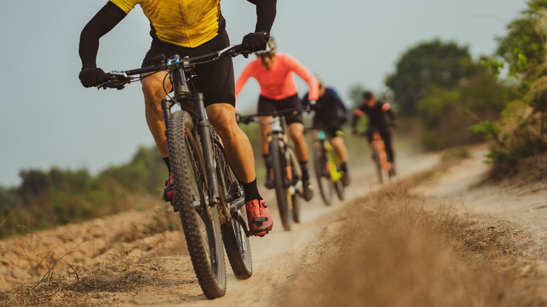 Four cyclists riding down muddy path