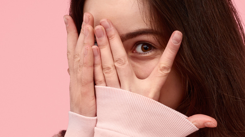 Embarrassed girl covering her face with hands