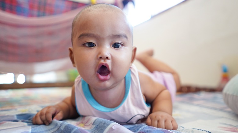 A baby laying and looking into the camera