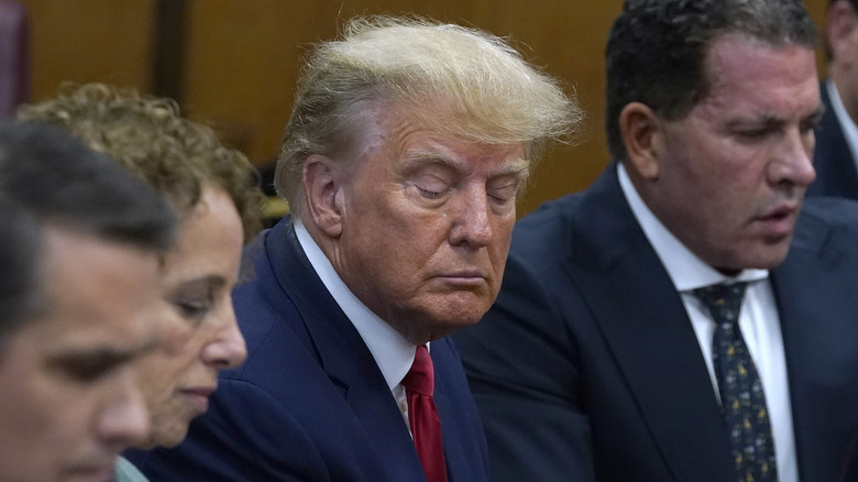 Trump eyes downcast between lawyers