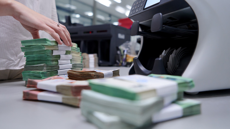 hand of bank teller counting stacks of money