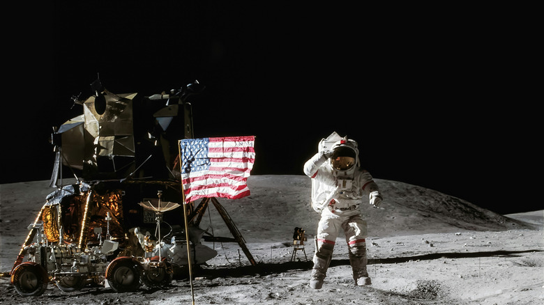 Astronaut saluting next to flag