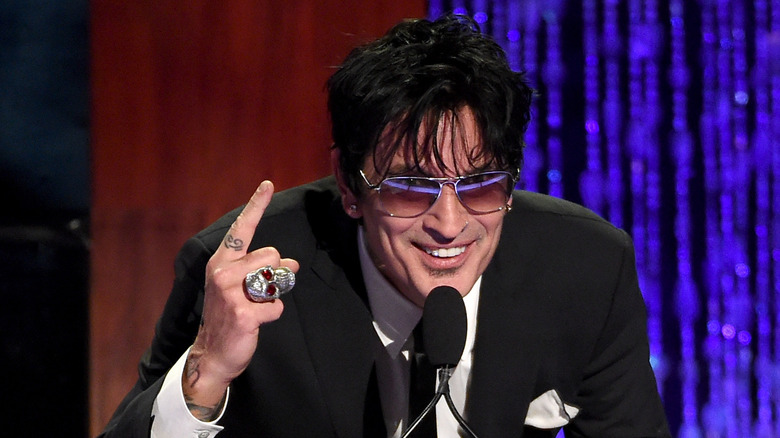 Tommy Lee onstage in glasses and suit