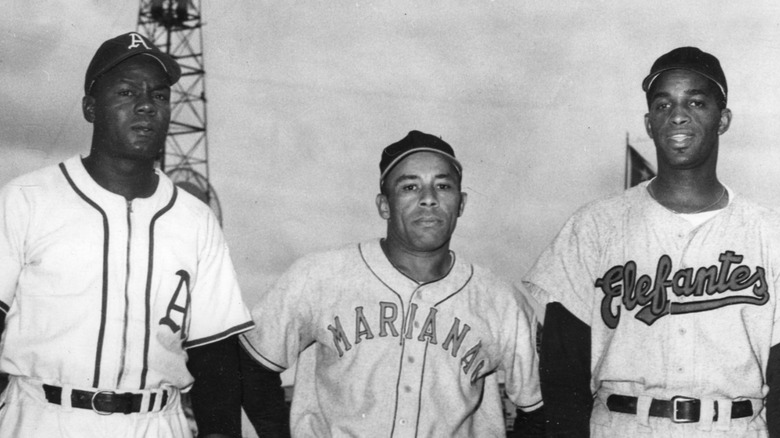 Three baseball players white shirts standing together in stadium