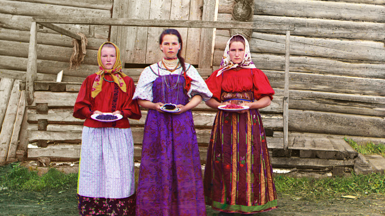 Peasant girls colored dresses wooden cabin