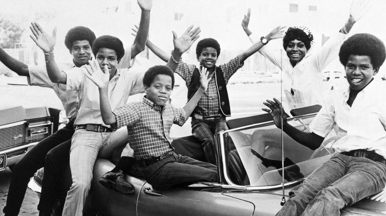 Diana Ross and Jackson 5 holding up arms in car