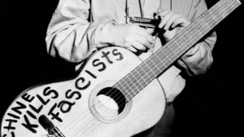 Woody Guthrie with guitar and harmonica