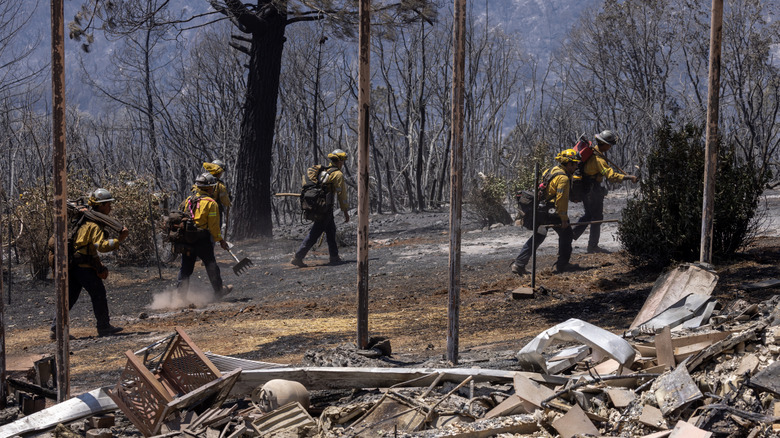firefighters walk by house destroyed by Camp Fire
