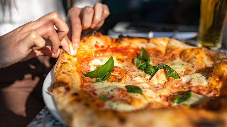 Woman pulling apart pizza slices