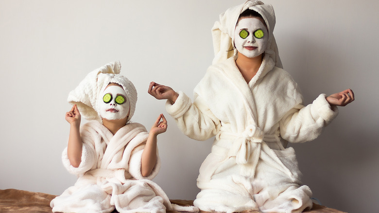 Mother and daughter in spa gear with cucumbers on eyes 