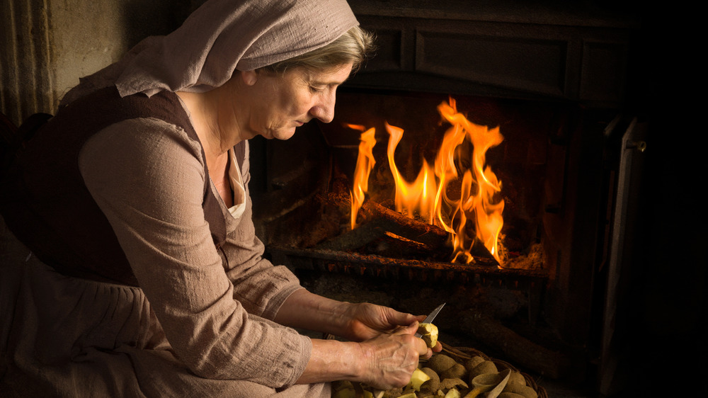 Renaissance old master portrait of a peasant woman peeling potatoes at her fireplace