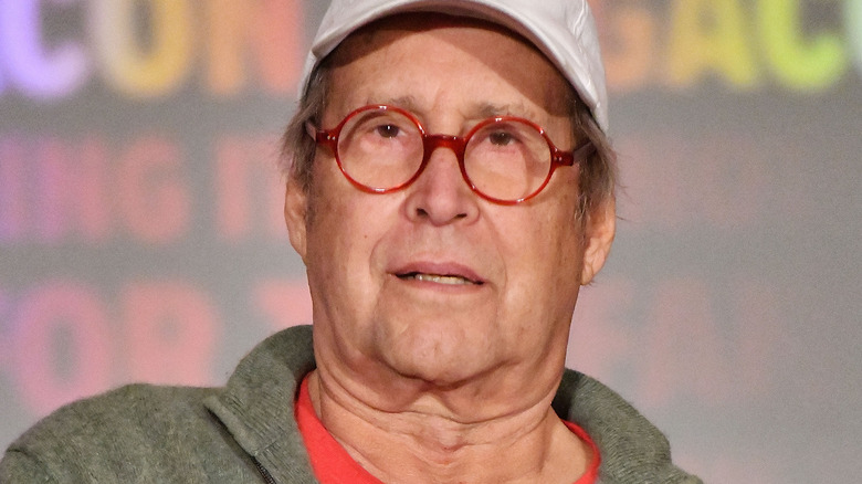 Chevy Chase in red glasses white cap